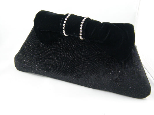 Black and Silver Clutch from Jenny Jag-Wear Design. Clutch is made from black holiday fabric with silver glitter. The black velvet bow provides the opening to the clutch. Rhinestones adorn the black bow. The Justina Collection from Jenny Jag-Wear Design.