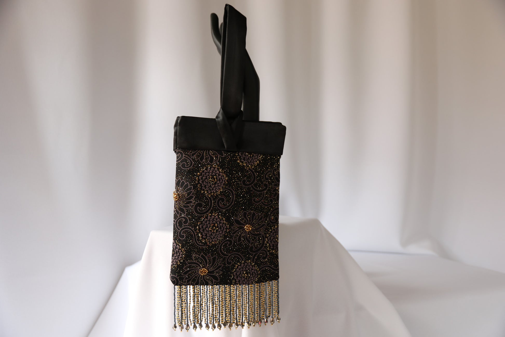 Black and Gold Evening Bag from Jenny Jag-Wear Design. This is a compact and functional ladies evening bag made from gold, grey and black knit, black satin trim and handle, and handcrafted beaded fringe. The oversized looped handle allows the user to pass the loop through her wrist, and keep hands free. Ideal wristlet design and very elegant. The Zara Collection from Jenny Jag-Wear Design.