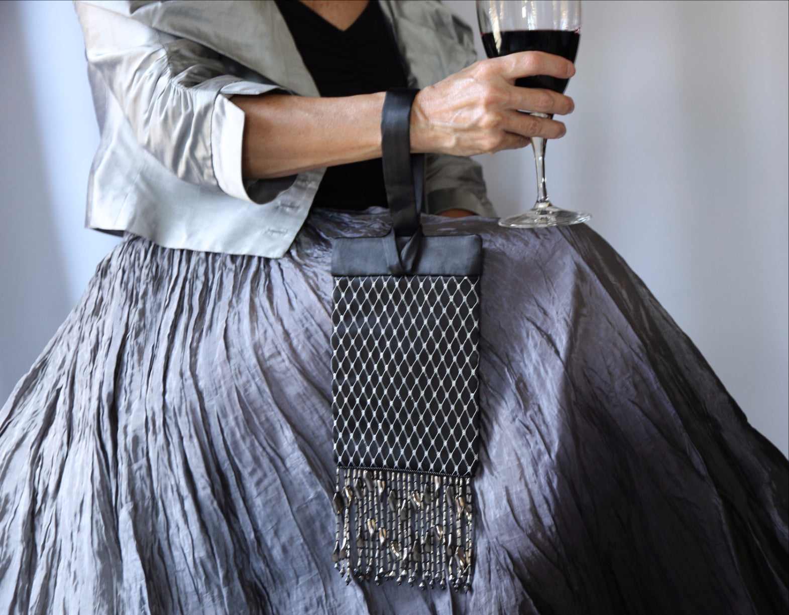 Black and Silver Evening Bag from Jenny Jag-Wear Design. The model demonstrates the functionality of this bag wearing the evening bag over her wrist, while easily holding a glass of wine. The Zara Collection by Jenny Jag-Wear Design.